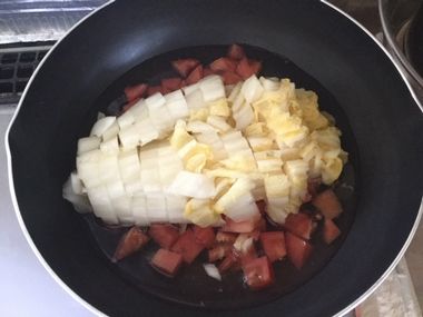 刻んだ白菜の漬物を汁ごと、刻んだトマトと一緒にフライパンに入れたところです。