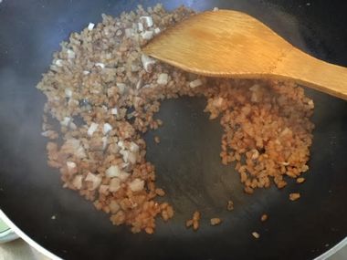 炊けた煎り玄米をヘラで混ぜながら、水分を飛ばしています。