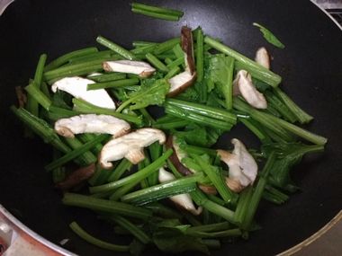 ホウレン草と椎茸をフライパンで炒めています。