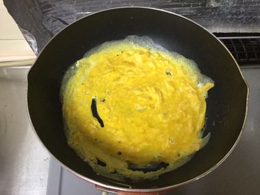 フライパンで卵を炒めています。