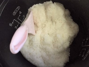 ヘラで米粒を潰そうとしています。