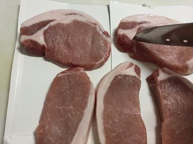 豚の厚切り肉に包丁を刺したところです。