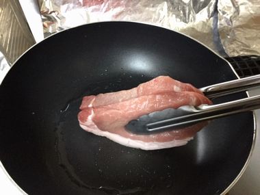 豚の厚切り肉の脂身を焼いている様子です。トングで挟んでします。