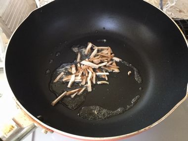 椎茸の軸をツナ缶の油で炒めています。